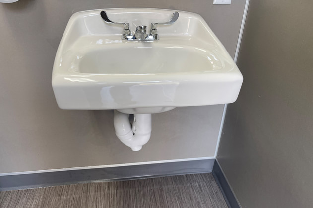 Wall-mounted bathroom sink installed with finished plumbing connections.